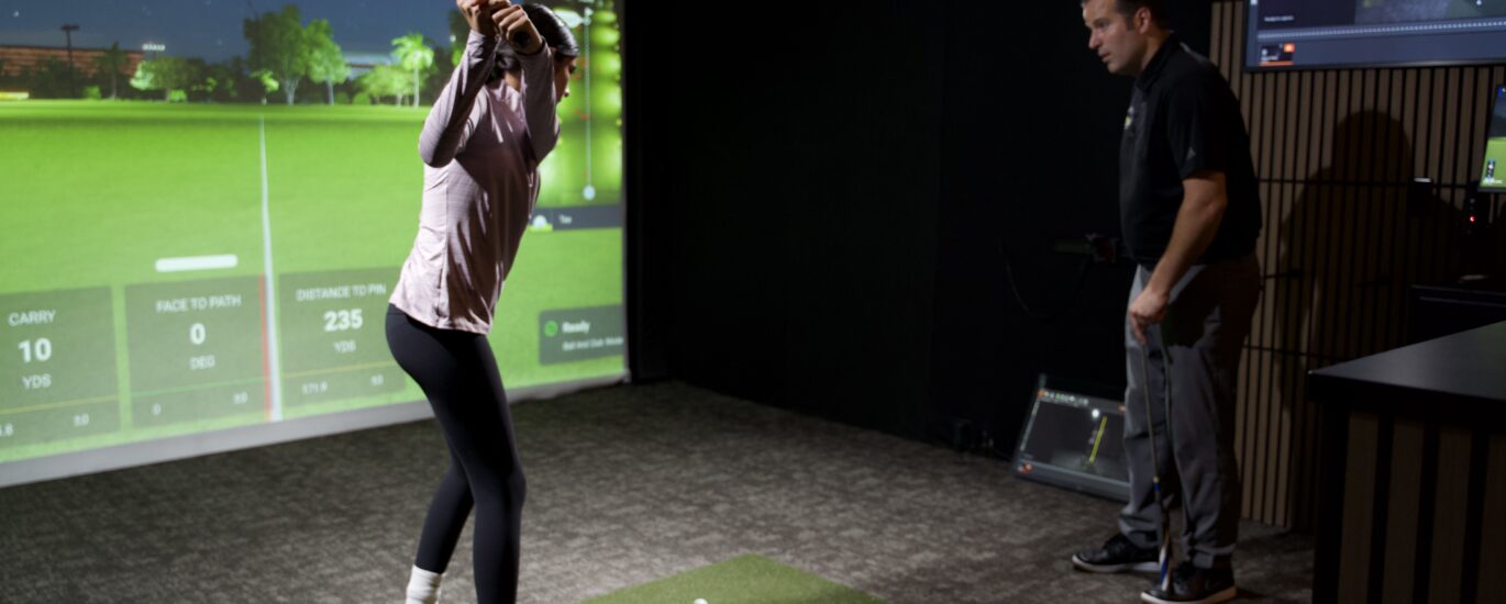 Junior golfer receiving a private golf lesson in an indoor simulator bay at Lago Golf in Port Coquitlam