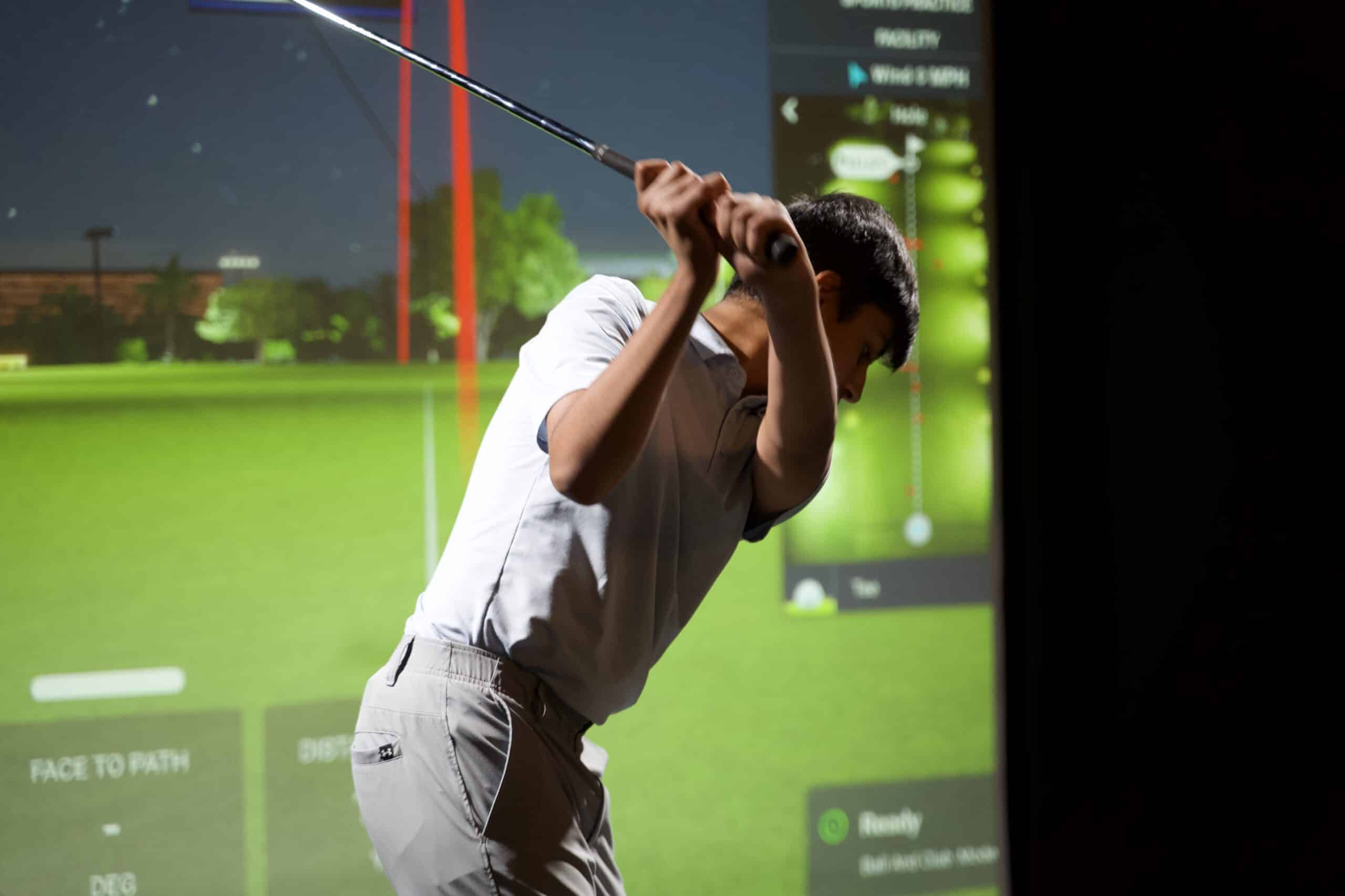 Junior golfer practising in Lago Golf's indoor simulator bay, included with a junior golf membership in Port Coquitlam