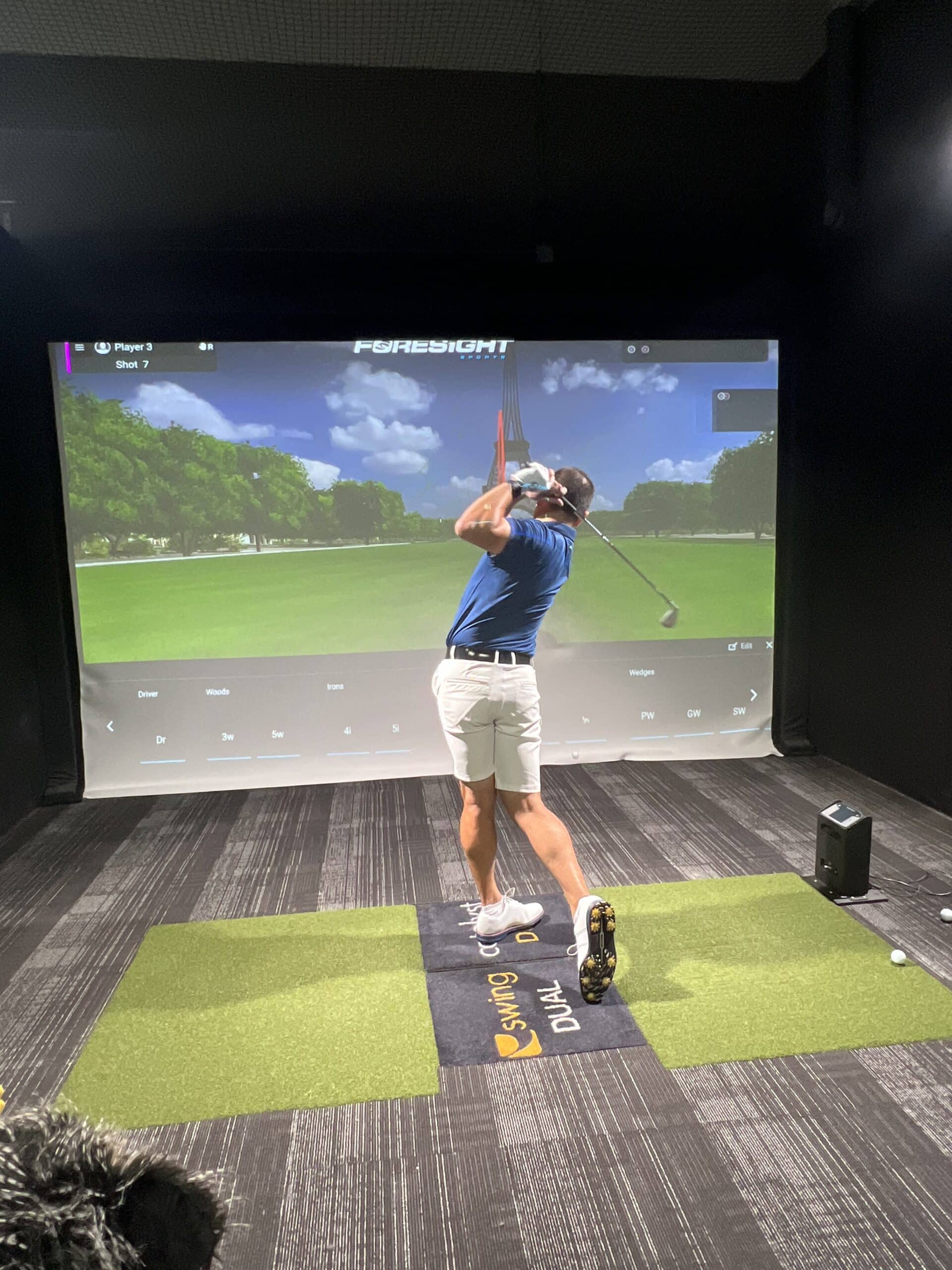 Lago Golf member hitting a shot in an indoor golf simulator bay