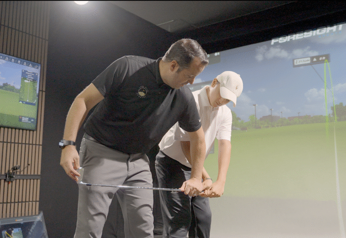 Junior golfer receiving a lesson in Lago Golf’s Golf Performance Lab in Port Coquitlam, BC as a coach works on swing technique