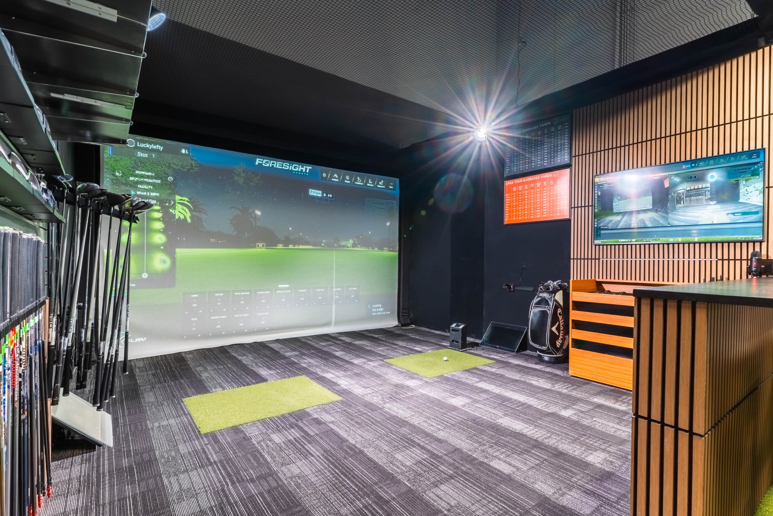 Club fitting bay at Lago Golf with a Foresight simulator screen and a rack of demo clubs