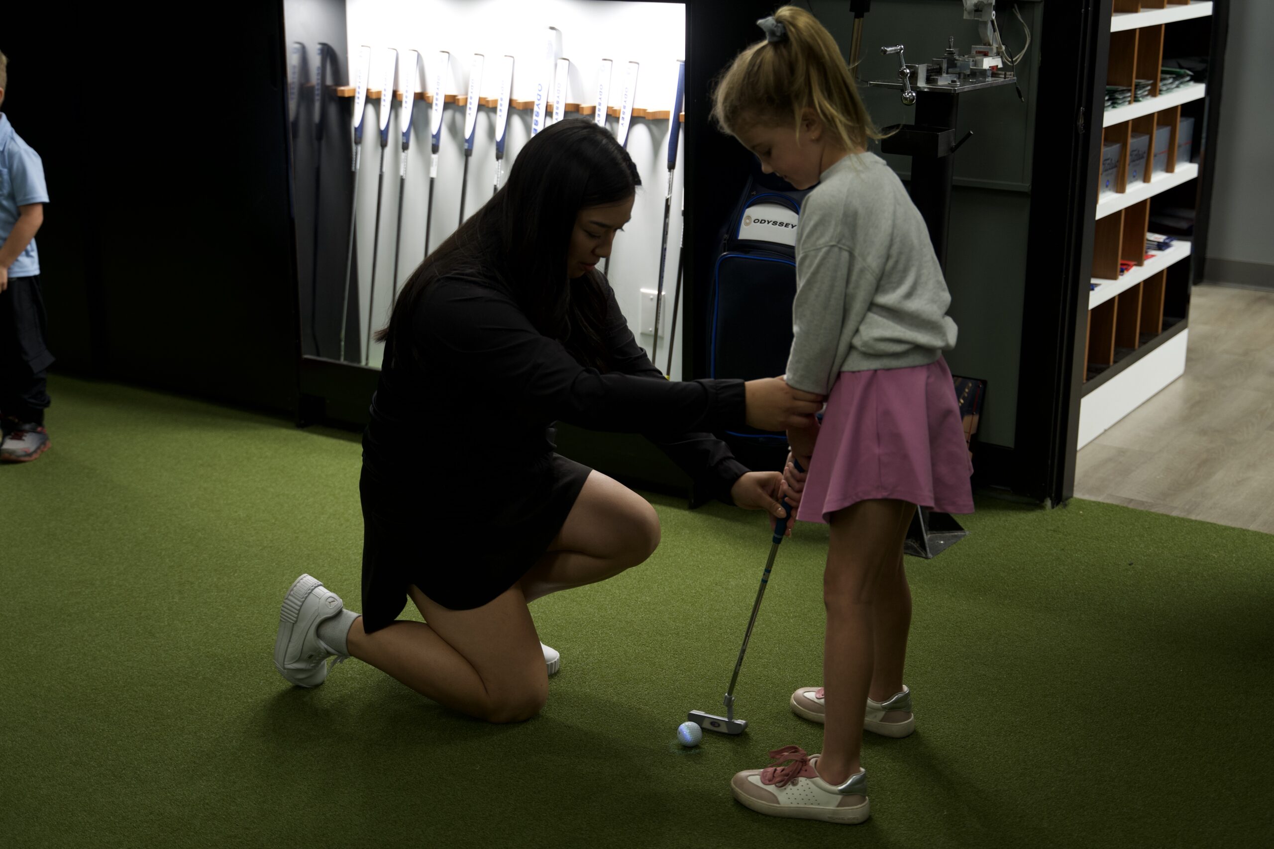 Golf instructor helping a young girl golfer with her grip during a girls-only junior lesson at Lago Golf